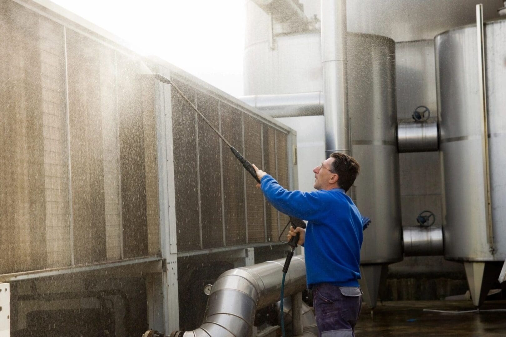 A man in blue jacket holding a hose.